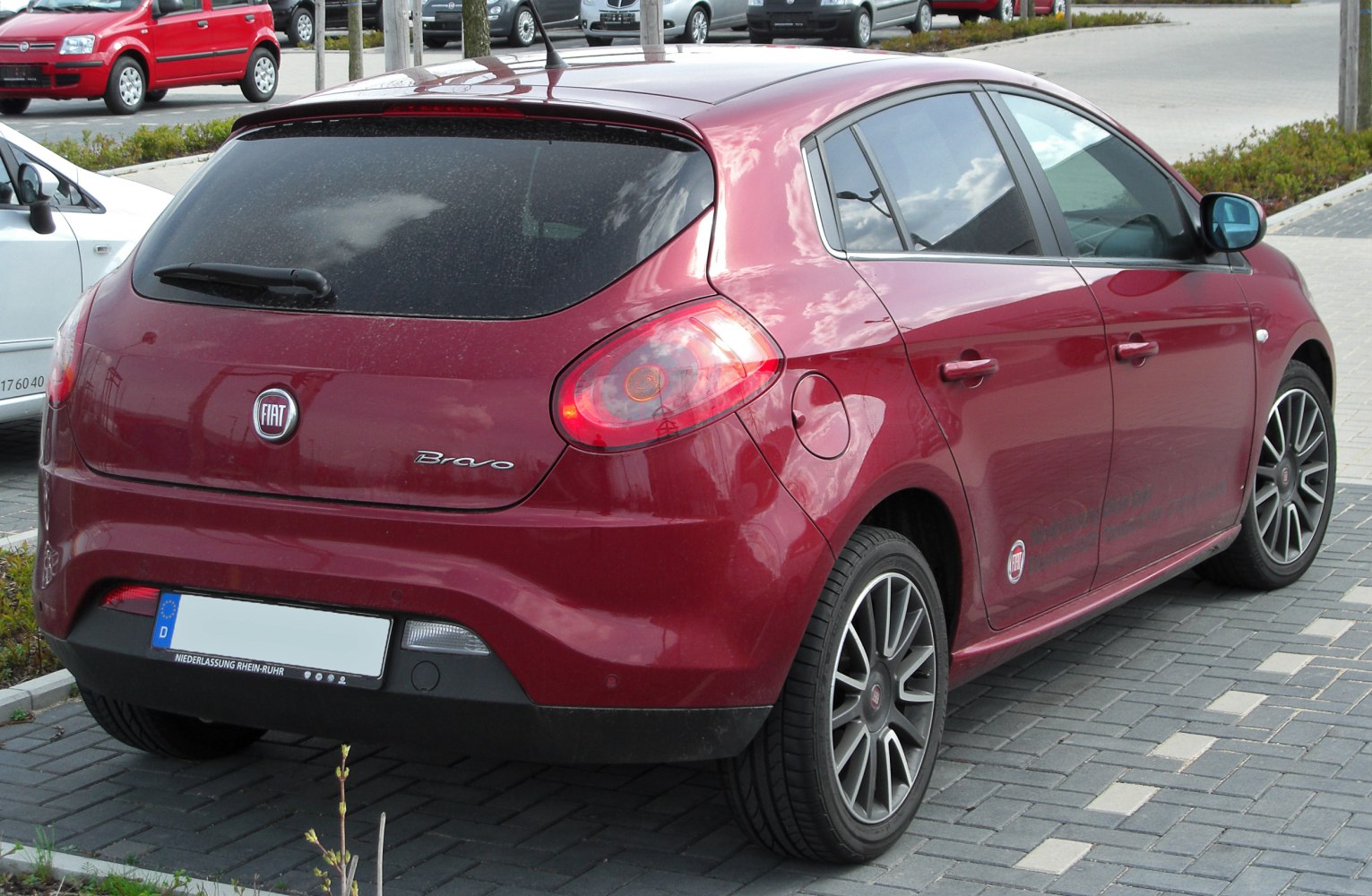 Red hatchback rear with distinct taillights, rear window wiper, and alloy wheels