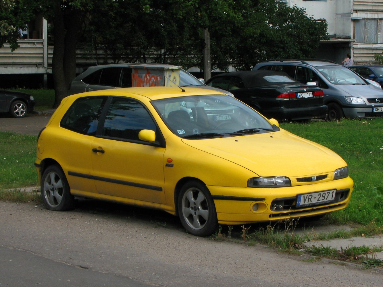 Yellow compact hatchback front and side view with distinct headlights and rounded body.