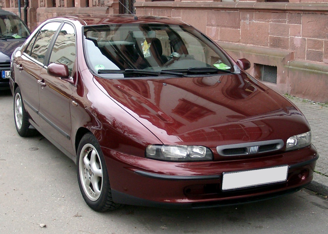 Front side view of a maroon sedan with alloy wheels