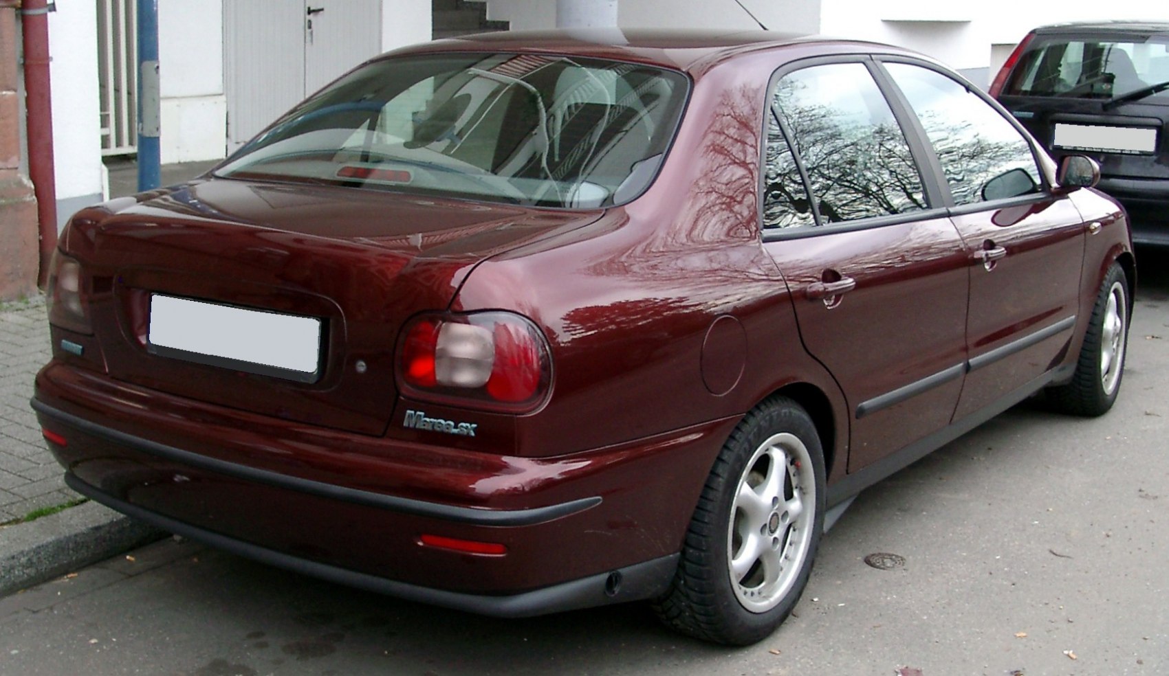 Rear and side view of a mid-90s four-door sedan with distinct tail lights.