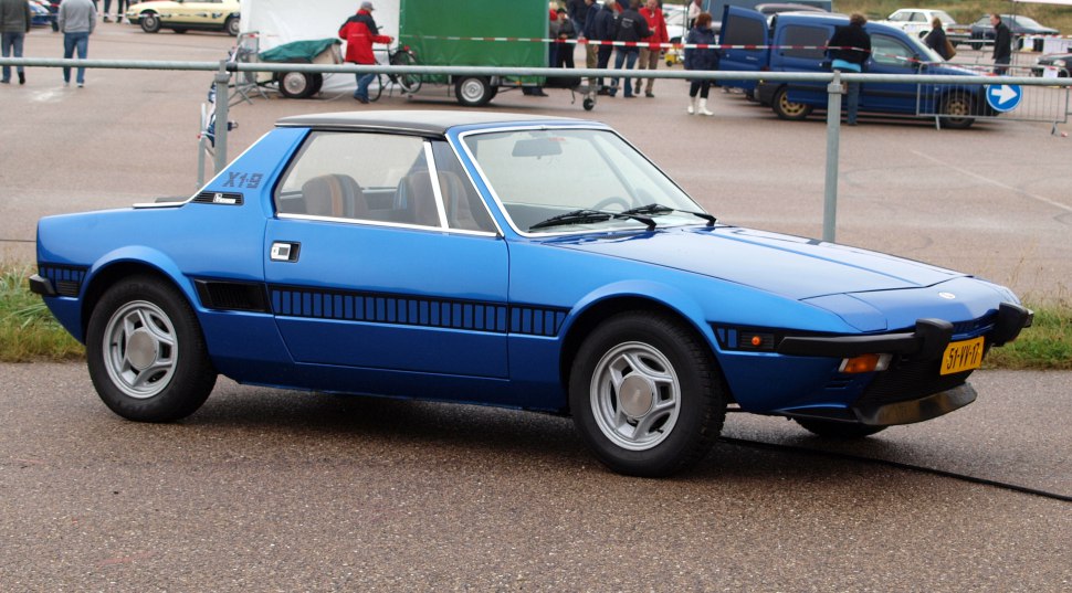 Blue wedge-shaped sports coupe with targa roof and distinctive side air intakes.