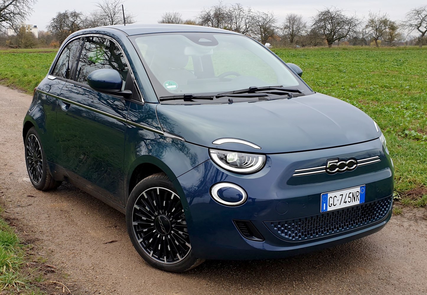 Compact electric hatchback with circular LED headlights and intricate multi-spoke alloy wheels