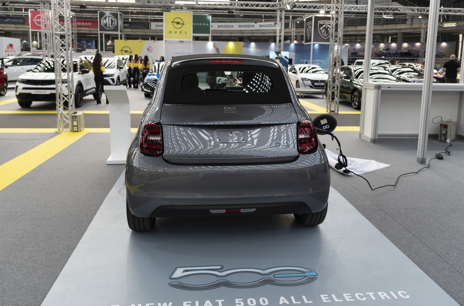 Rear view of compact electric car plugged in for charging.