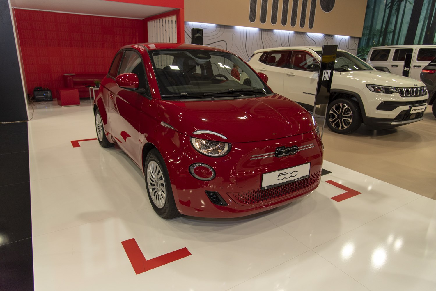 Red compact electric hatchback with round headlights and distinctive grille