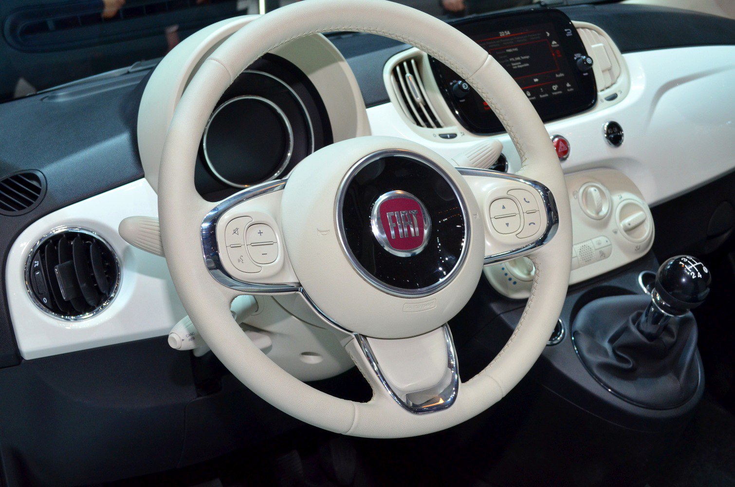 White leather steering wheel and manual gear shift with dashboard controls