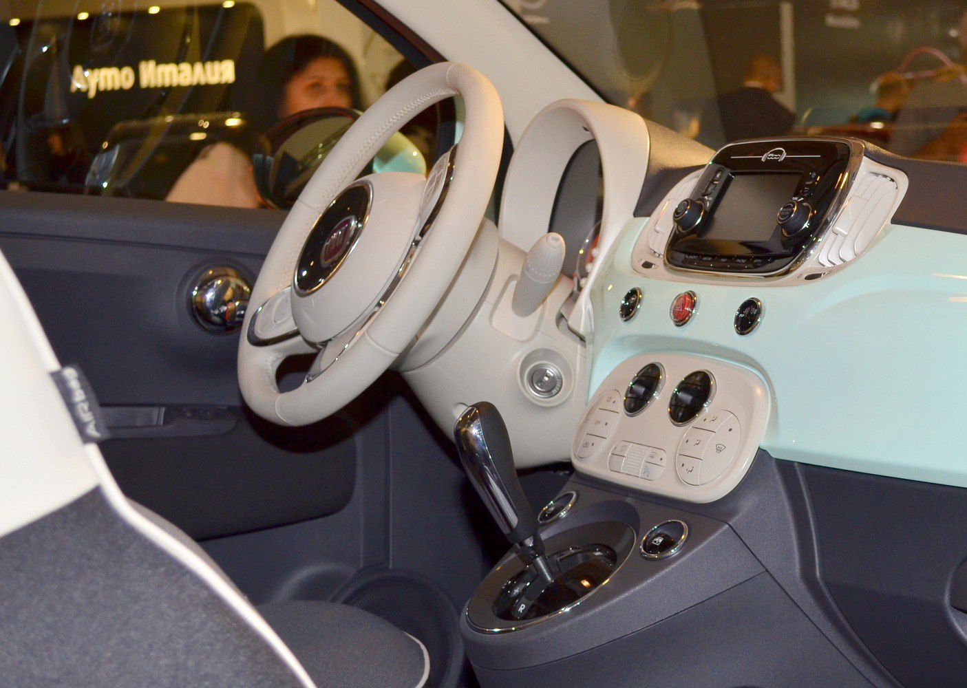 Steering wheel, dashboard, gear shifter, and controls in a compact car interior.