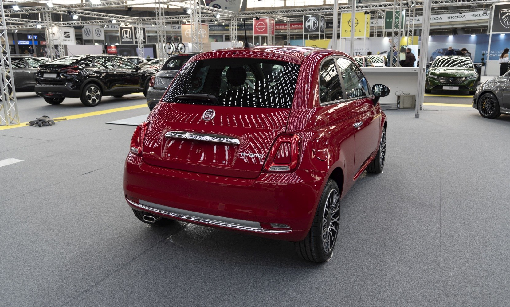 Red compact car rear with hybrid badge and alloy wheels