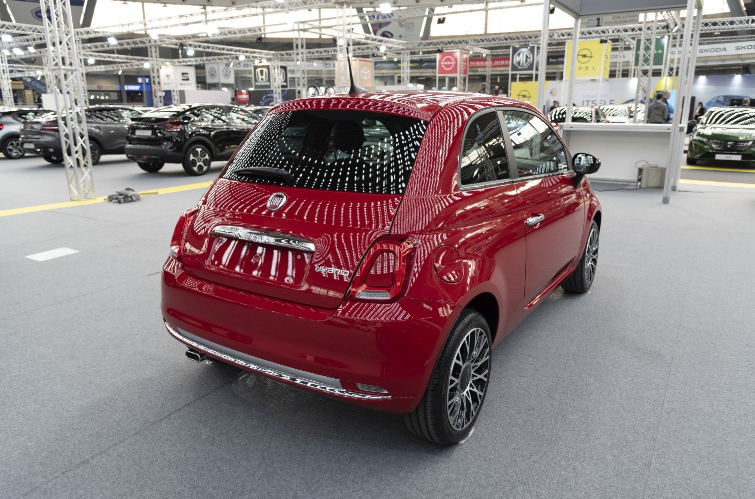 Rear and side view of red compact hatchback with hybrid badge and alloy wheels