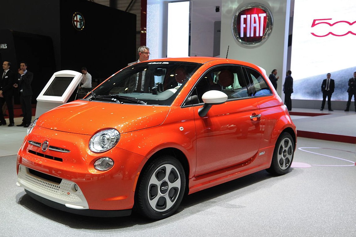 Front-side view of orange electric compact car with round headlights