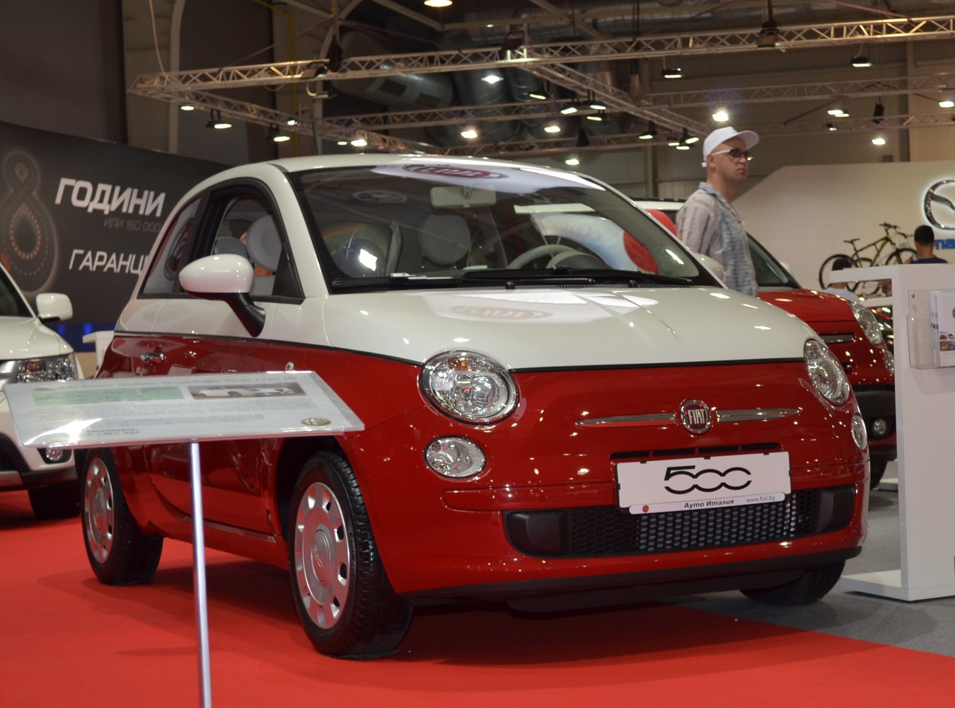 Two-tone red and white compact hatchback with retro design and round headlights.