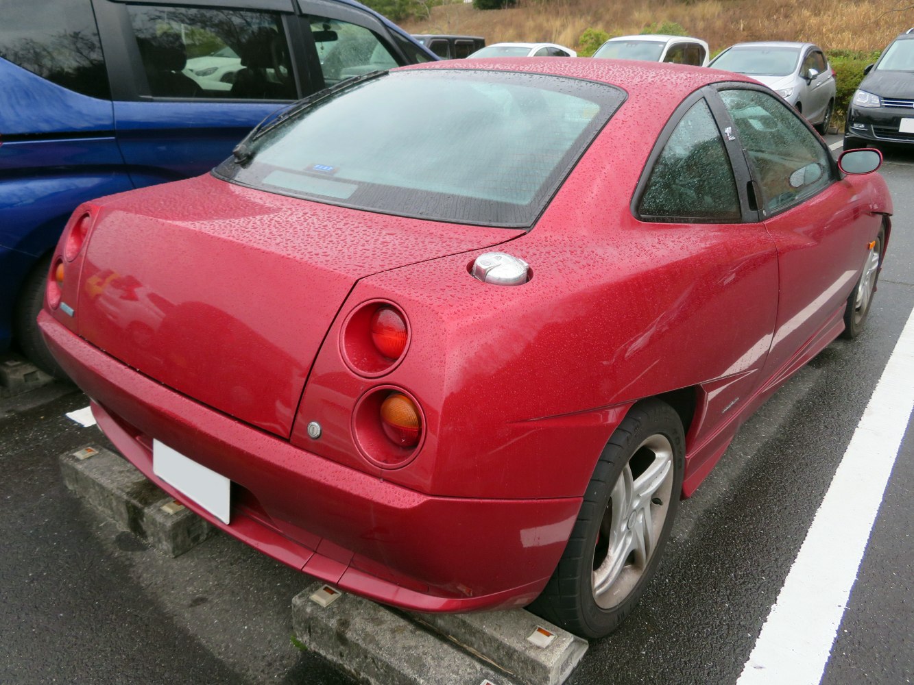 Red hatchback coupe rear with round taillights and exposed fuel cap