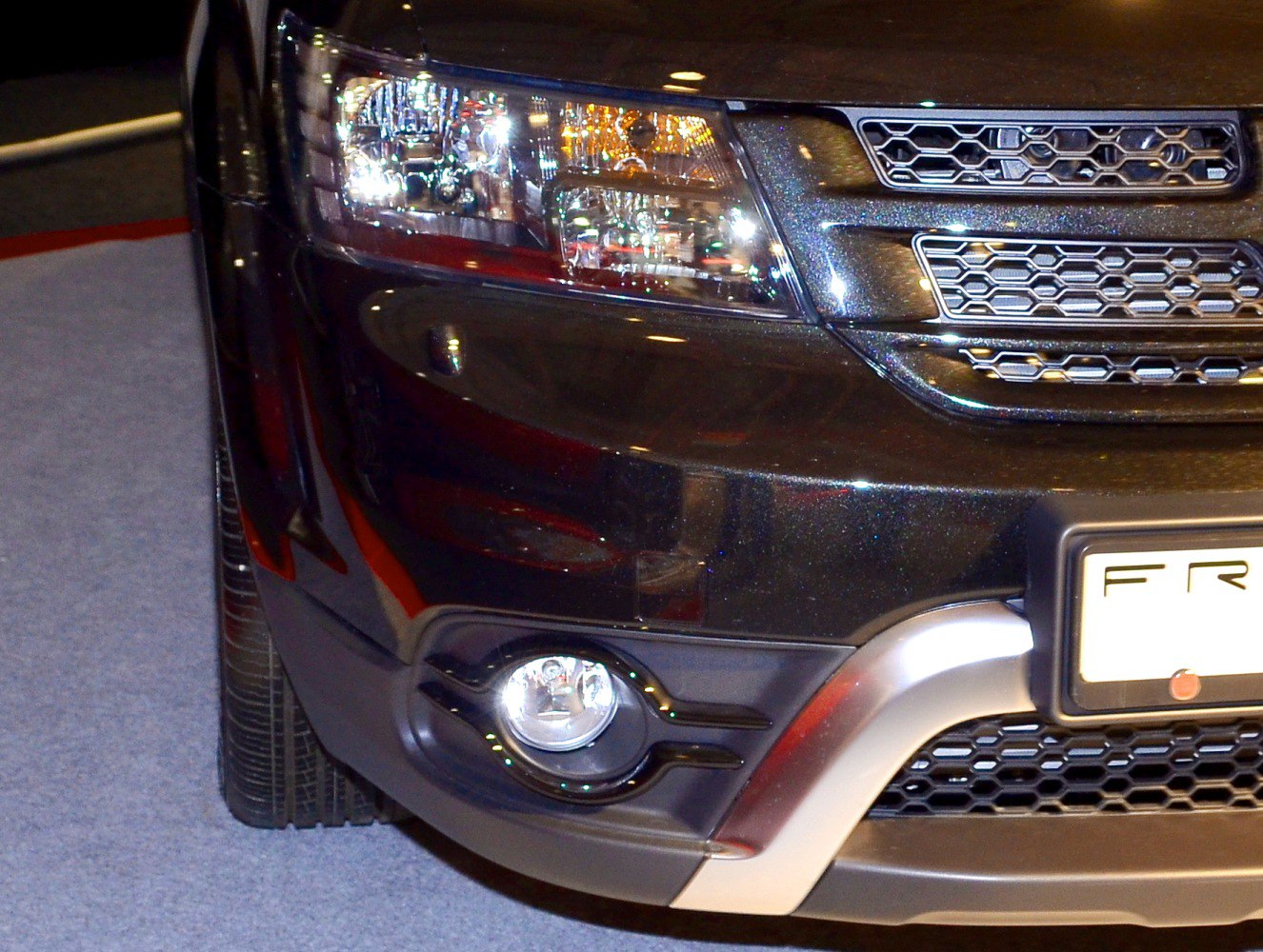 Close-up of front headlight, fog light, and honeycomb grille