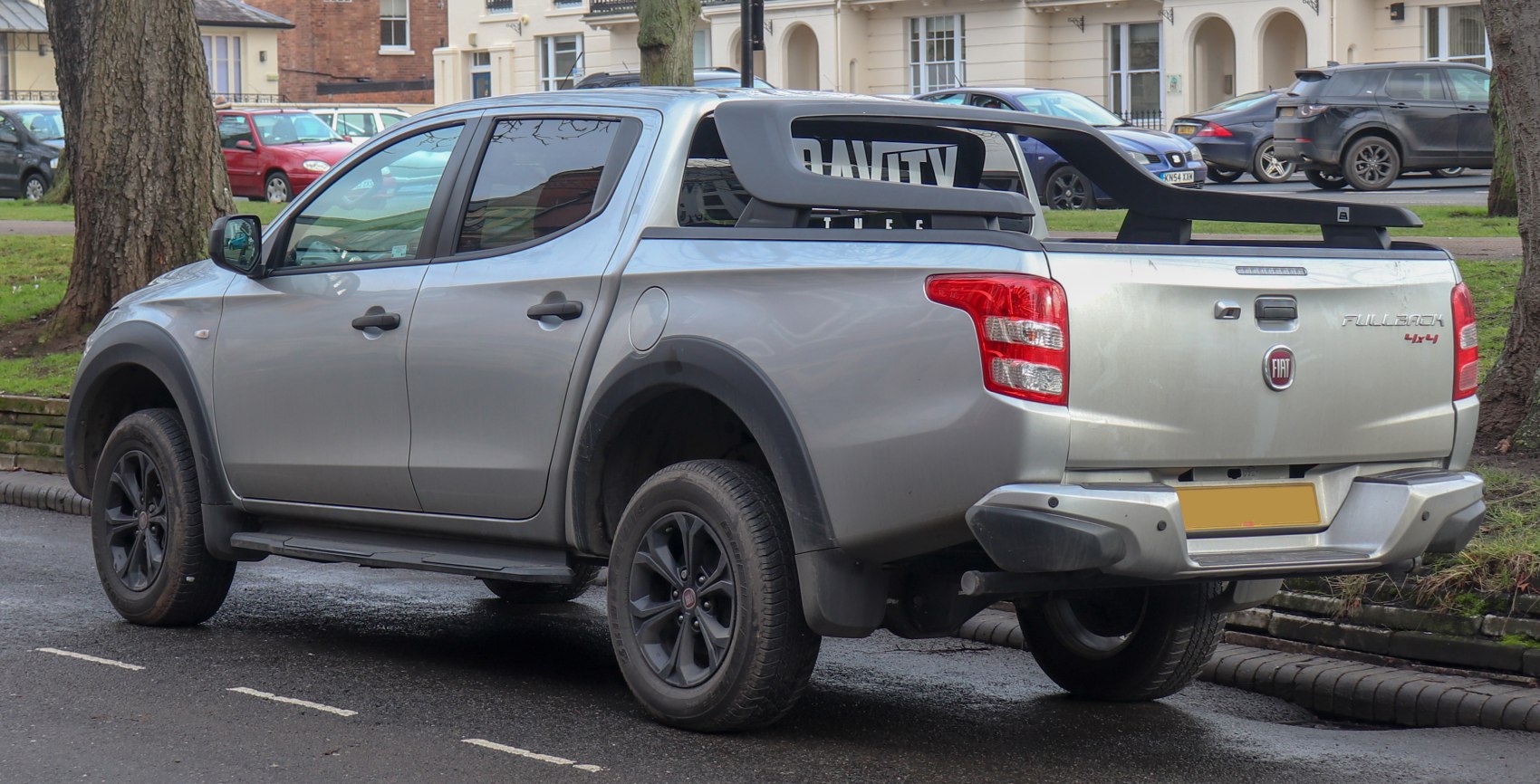 Silver double cab pickup with black wheels and rear bed roof rack