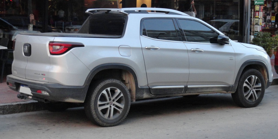 Silver pickup truck, rear side view with roof rack and rugged tires