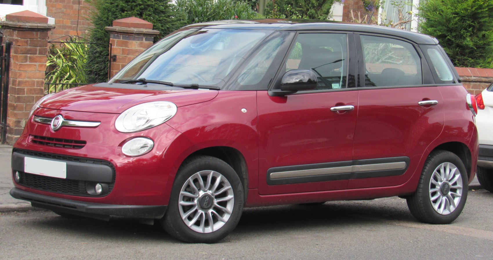 Red compact MPV with black roof and alloy wheels in side front view