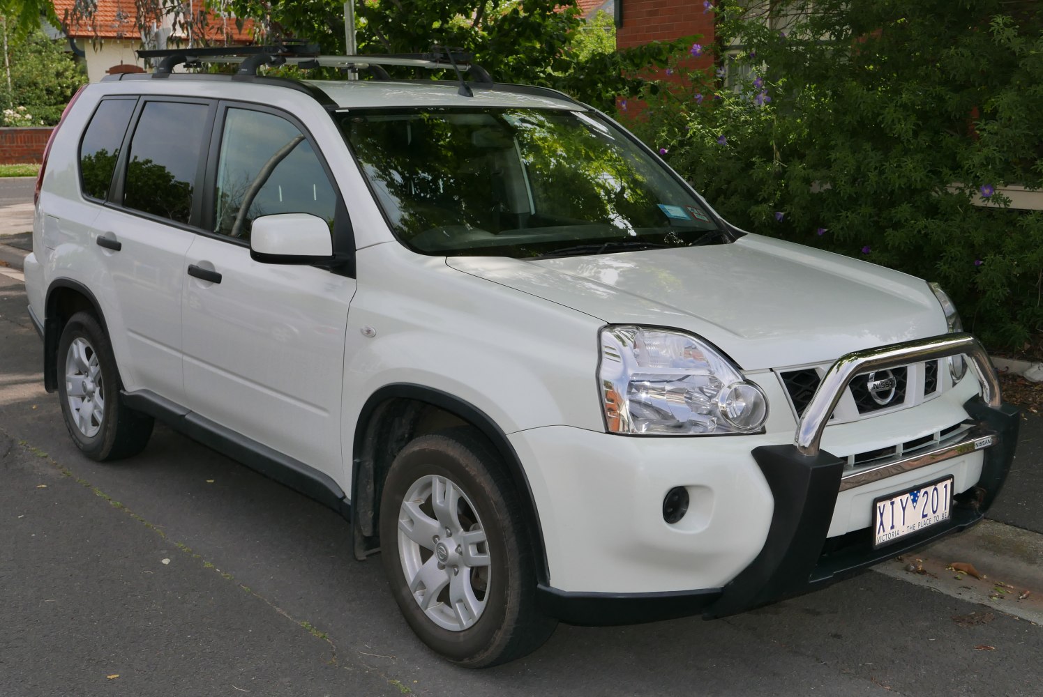 White SUV with chrome bull bar, roof rack, and alloy wheels