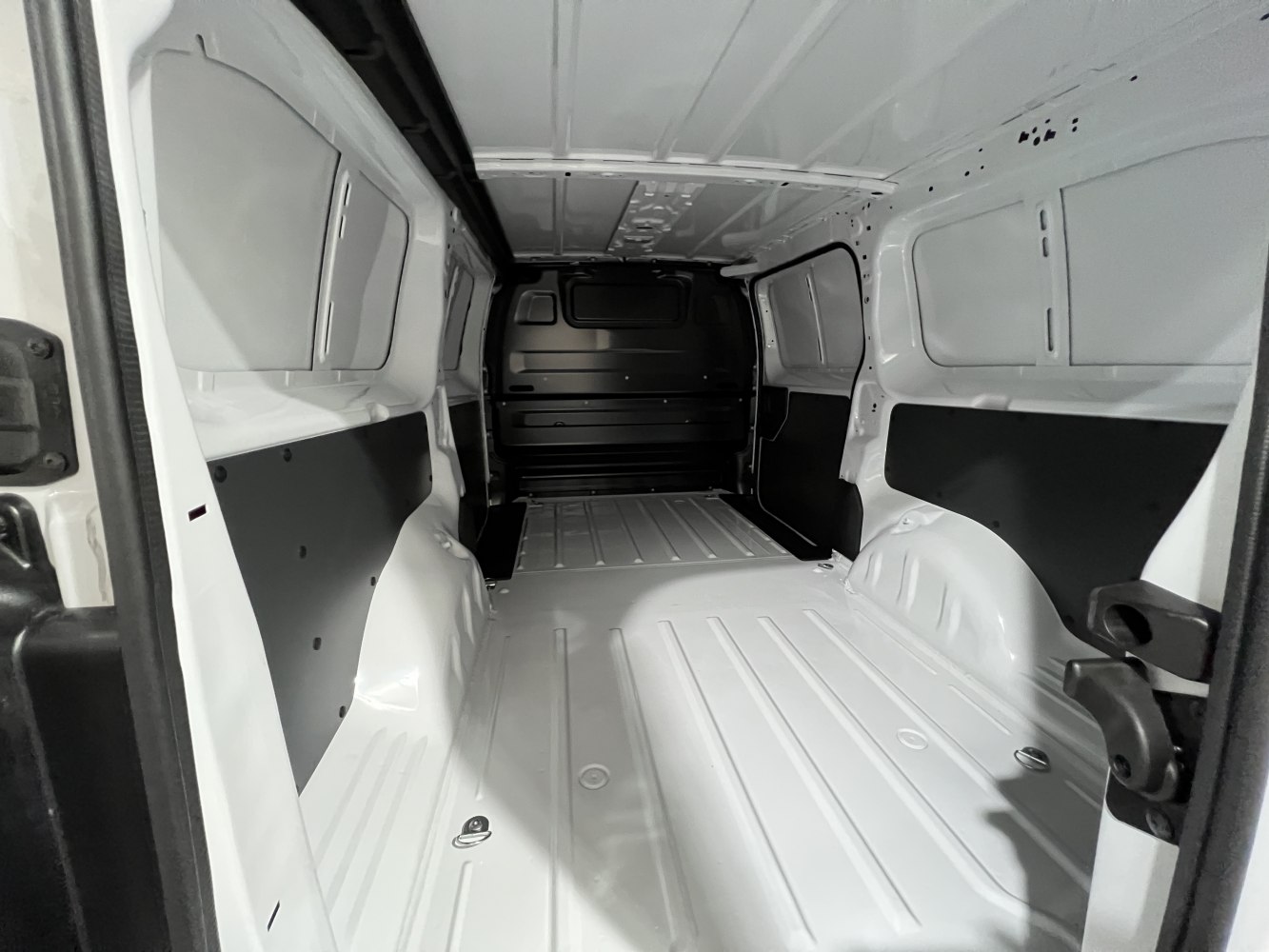 Empty cargo space with ribbed floor and protective paneling.