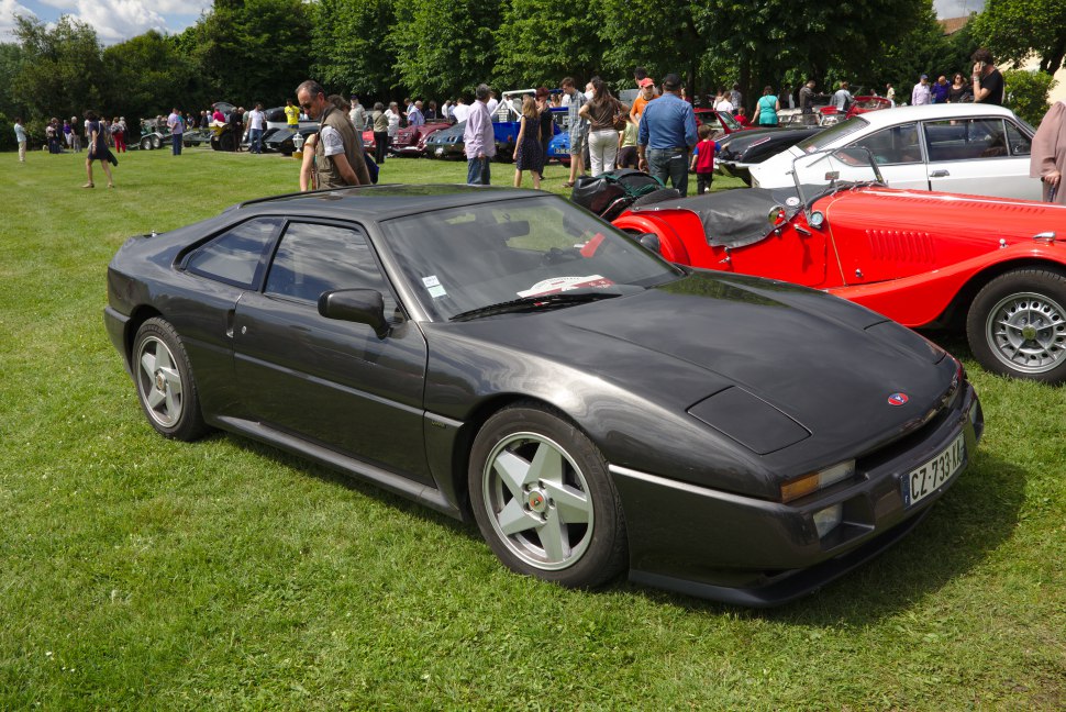 Sleek black sports coupe with pop-up headlights and alloy wheels.