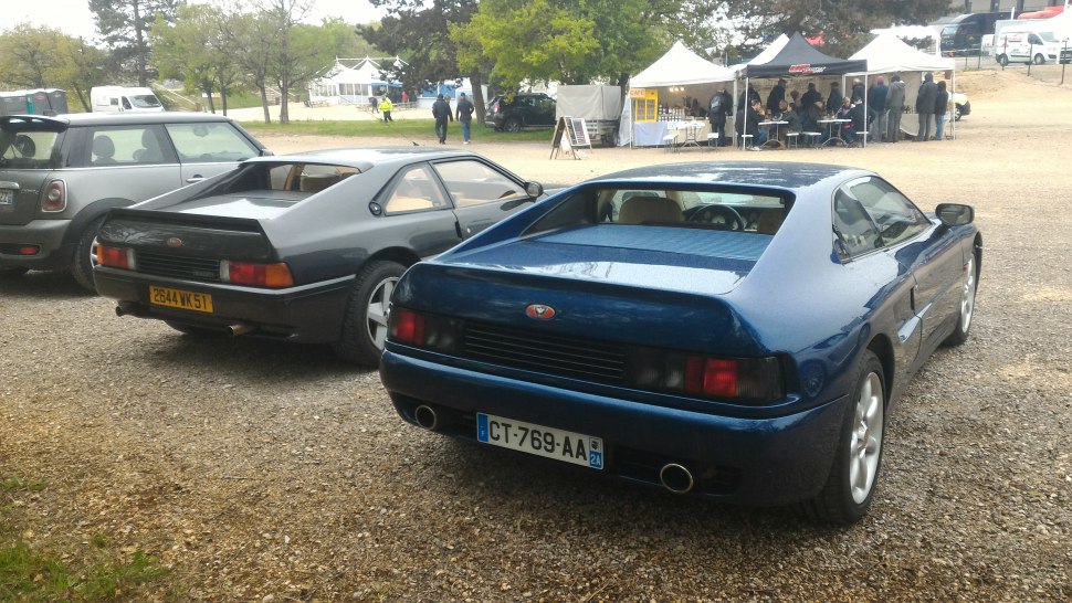 Rear view of two vintage sports coupes with distinctive tail lights and streamlined rear designs