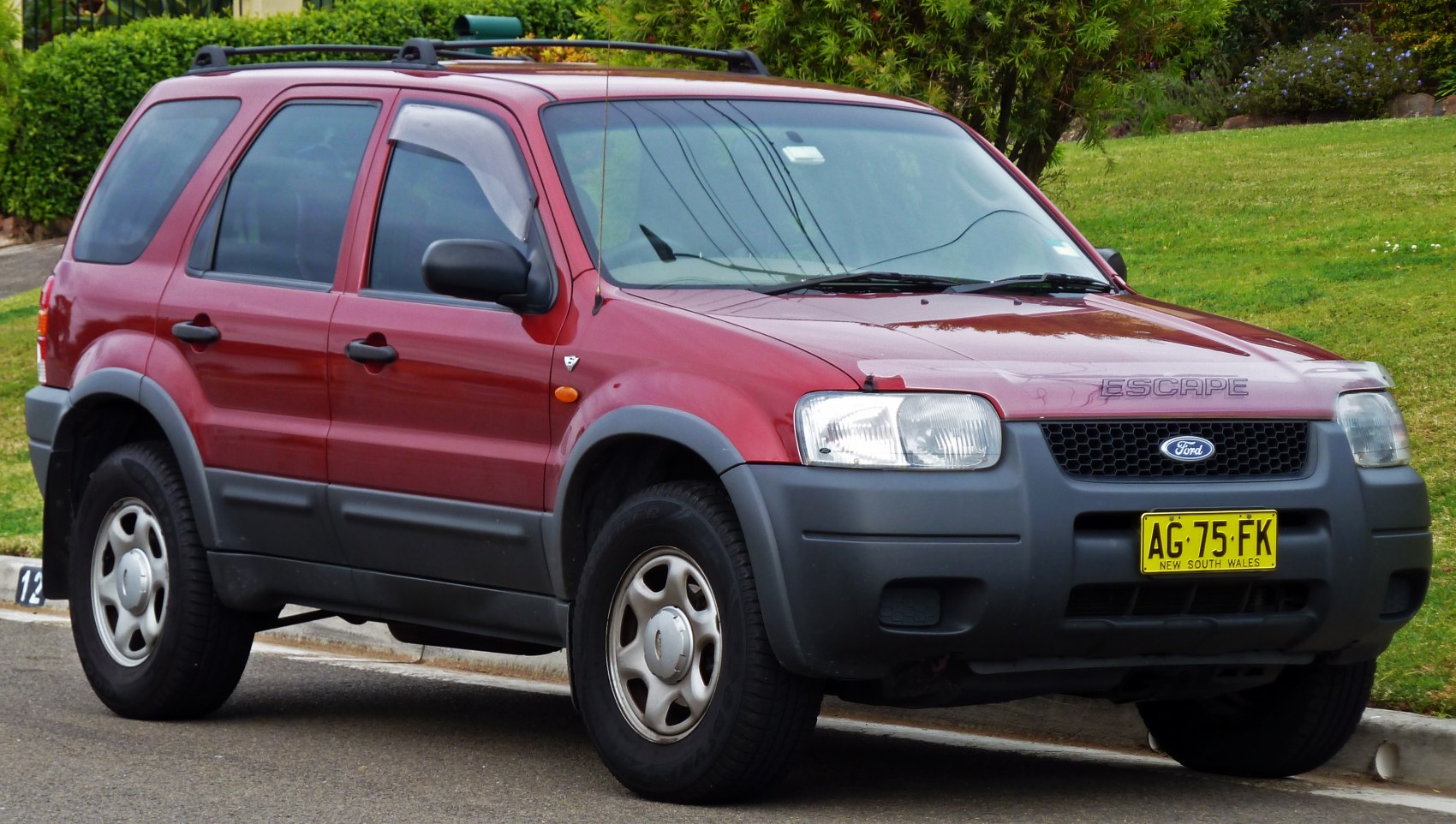 Red SUV with rugged black trim and roof rails, front side view.