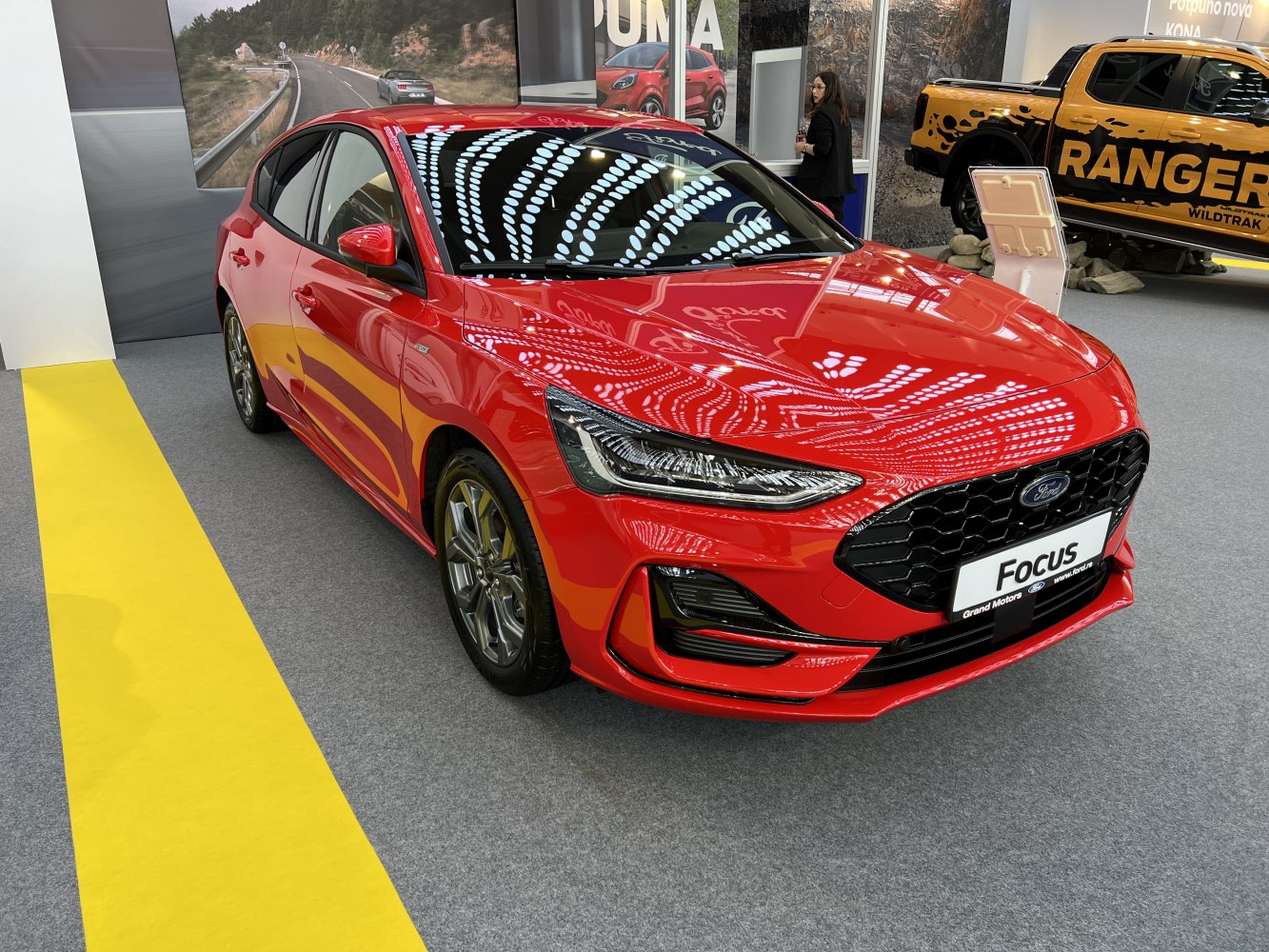 Red modern hatchback with LED headlights and black honeycomb grille