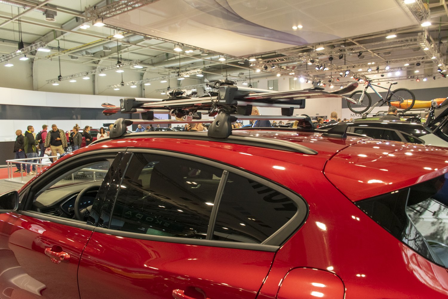 Red hatchback with roof-rack mounted skis