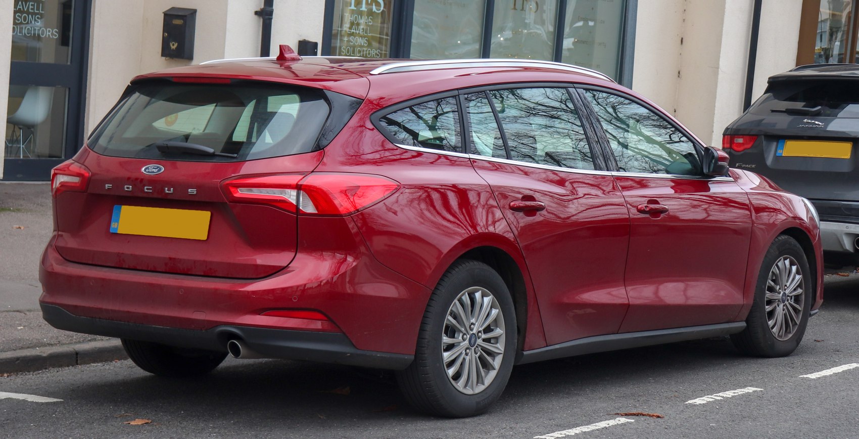 Rear side profile of a red wagon with detailed tail lights and roof rails.
