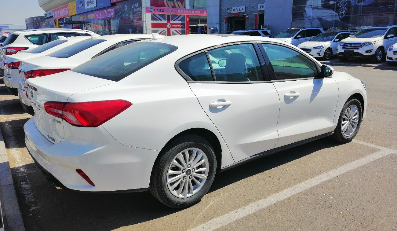 White sedan rear side view with alloy wheels and rear light cluster.