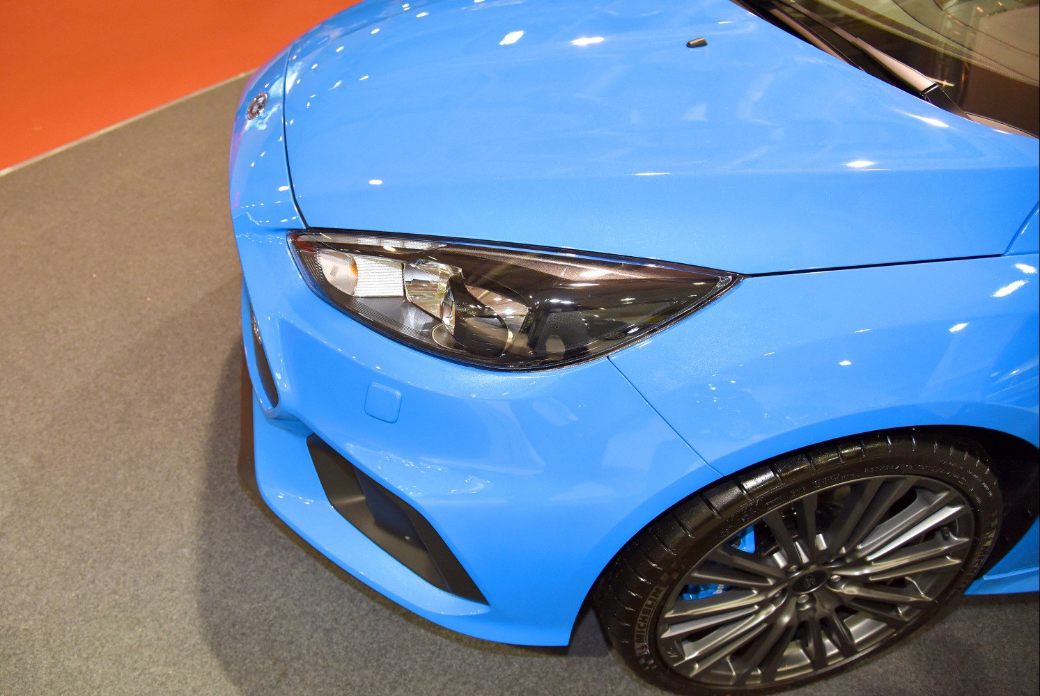 Close-up of headlight and alloy wheel on blue hatchback front end