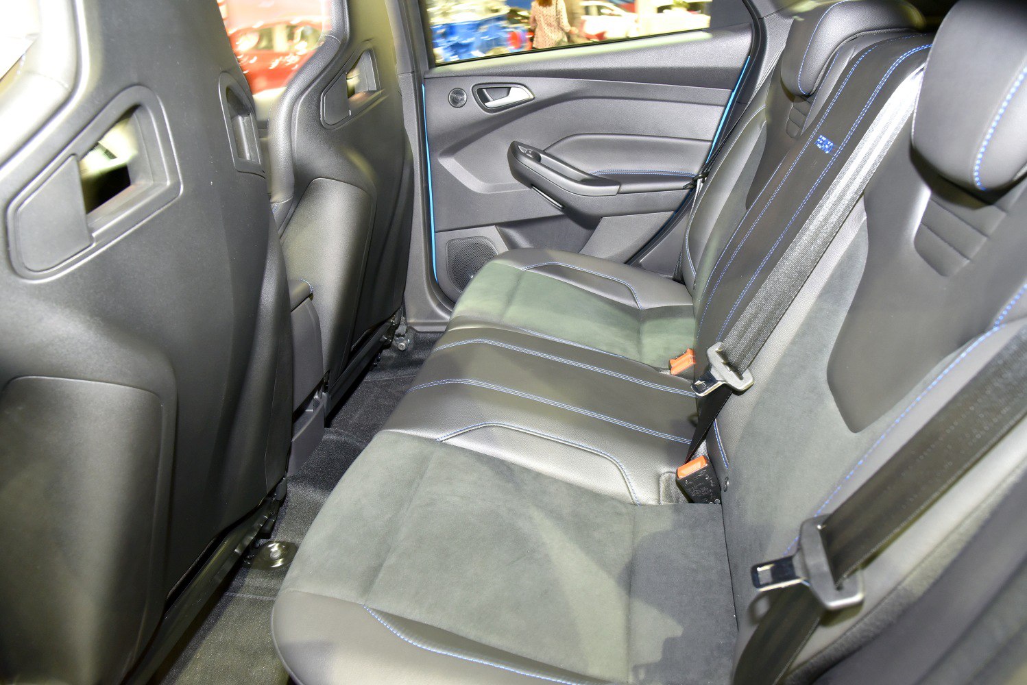 Rear seat upholstery with blue stitching and seat belts