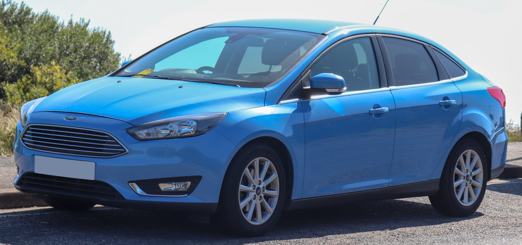 Front-side view of a blue sedan with sleek headlights and alloy wheels