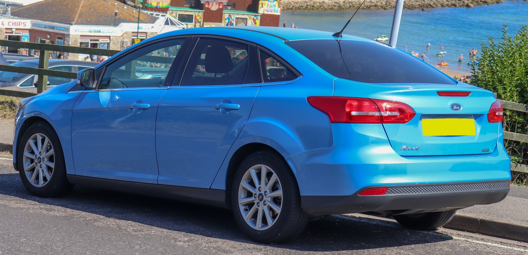 Rear side view of a blue sedan with facelift taillights and alloy wheels