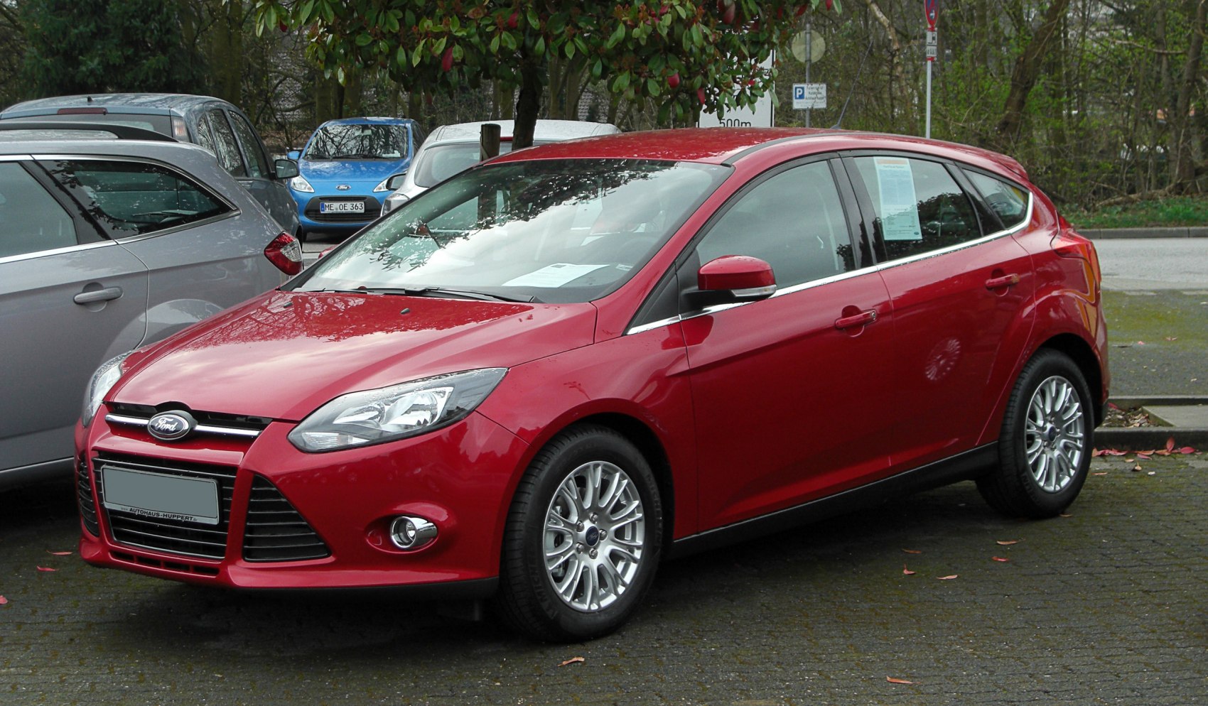 Front and side view of a red hatchback car with alloy wheels