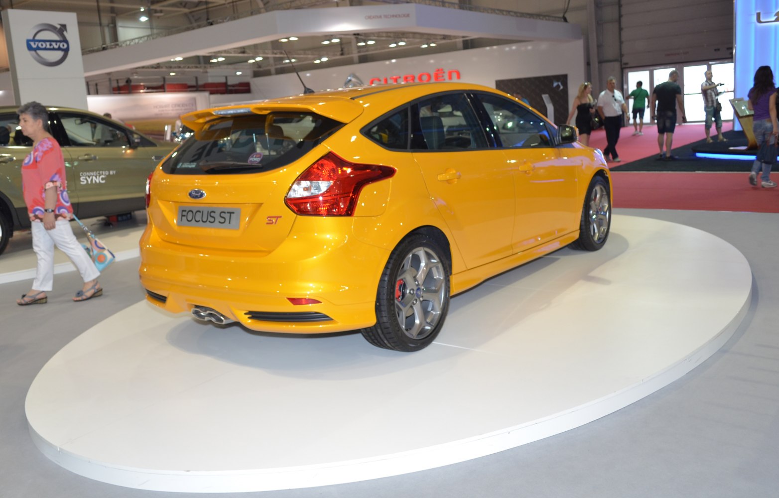 Sporty hatchback with prominent rear spoiler, dual exhaust, and alloy wheels in bright yellow.