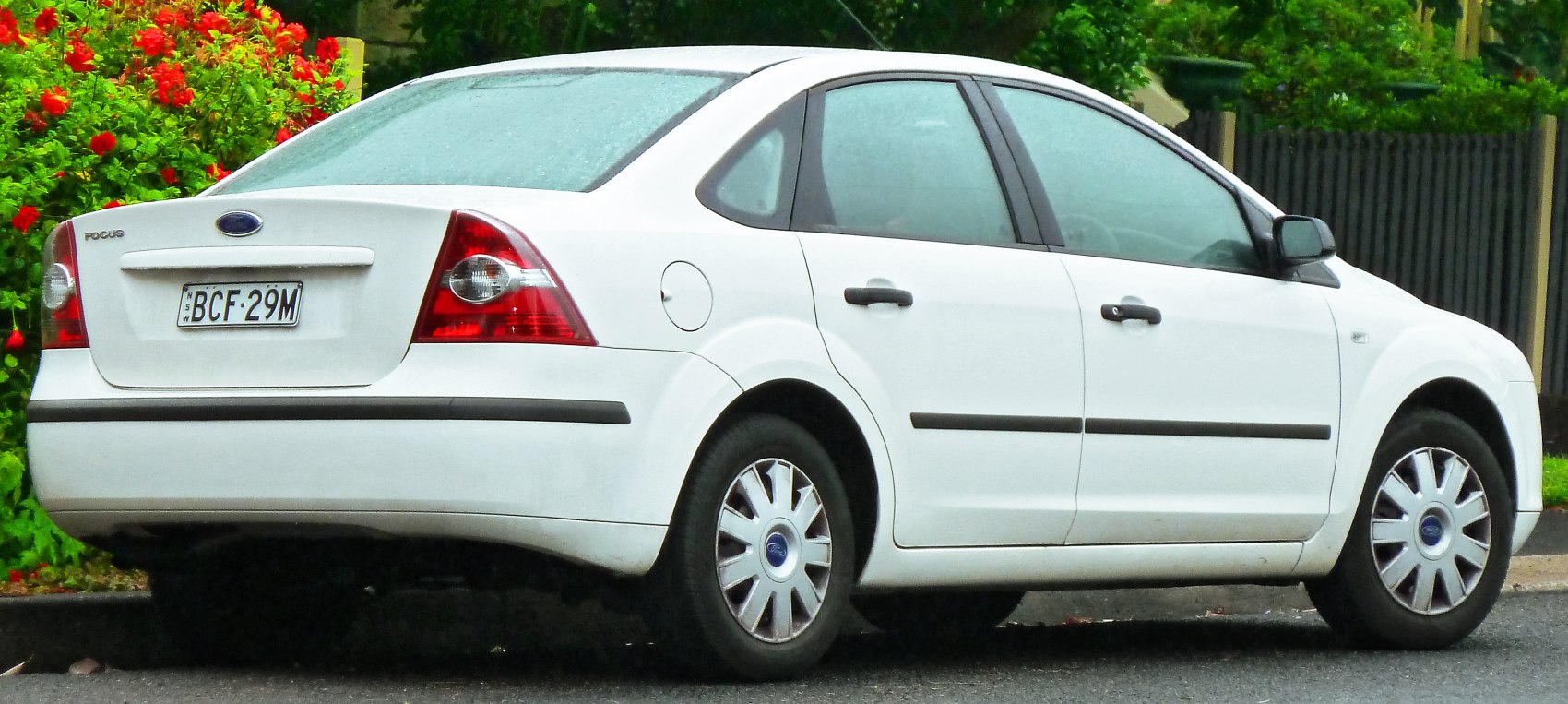 Rear side of white sedan with distinct tail lights and classic wheel covers