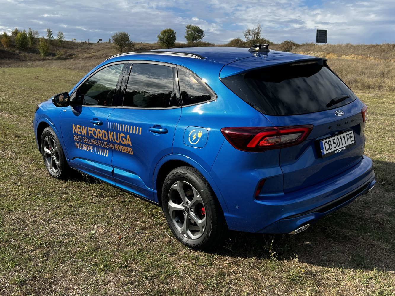 Rear-side view of hybrid SUV with plug-in charging sign and modern taillights