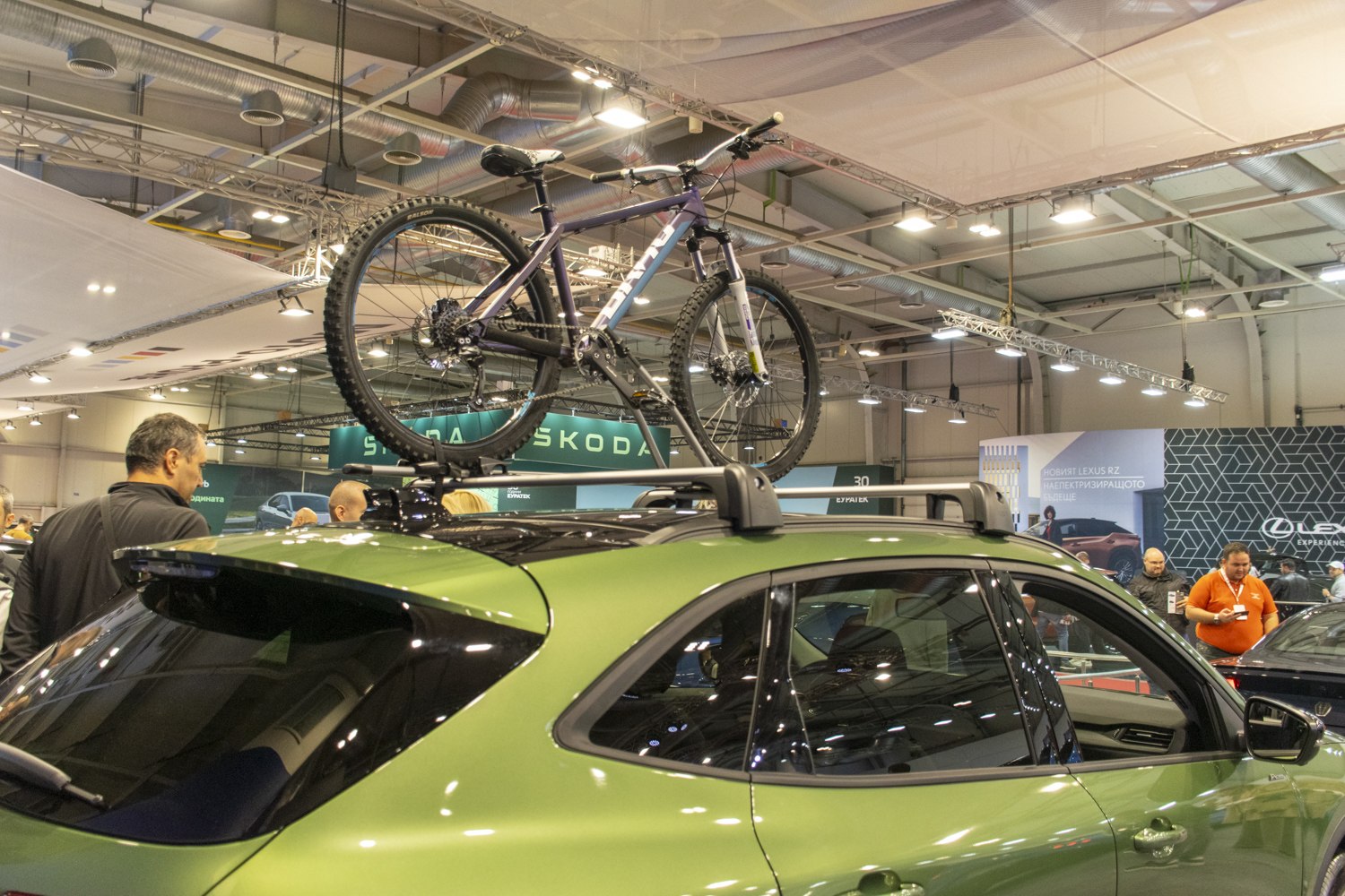 Green SUV roof with mountain bike mounted on rails indoors