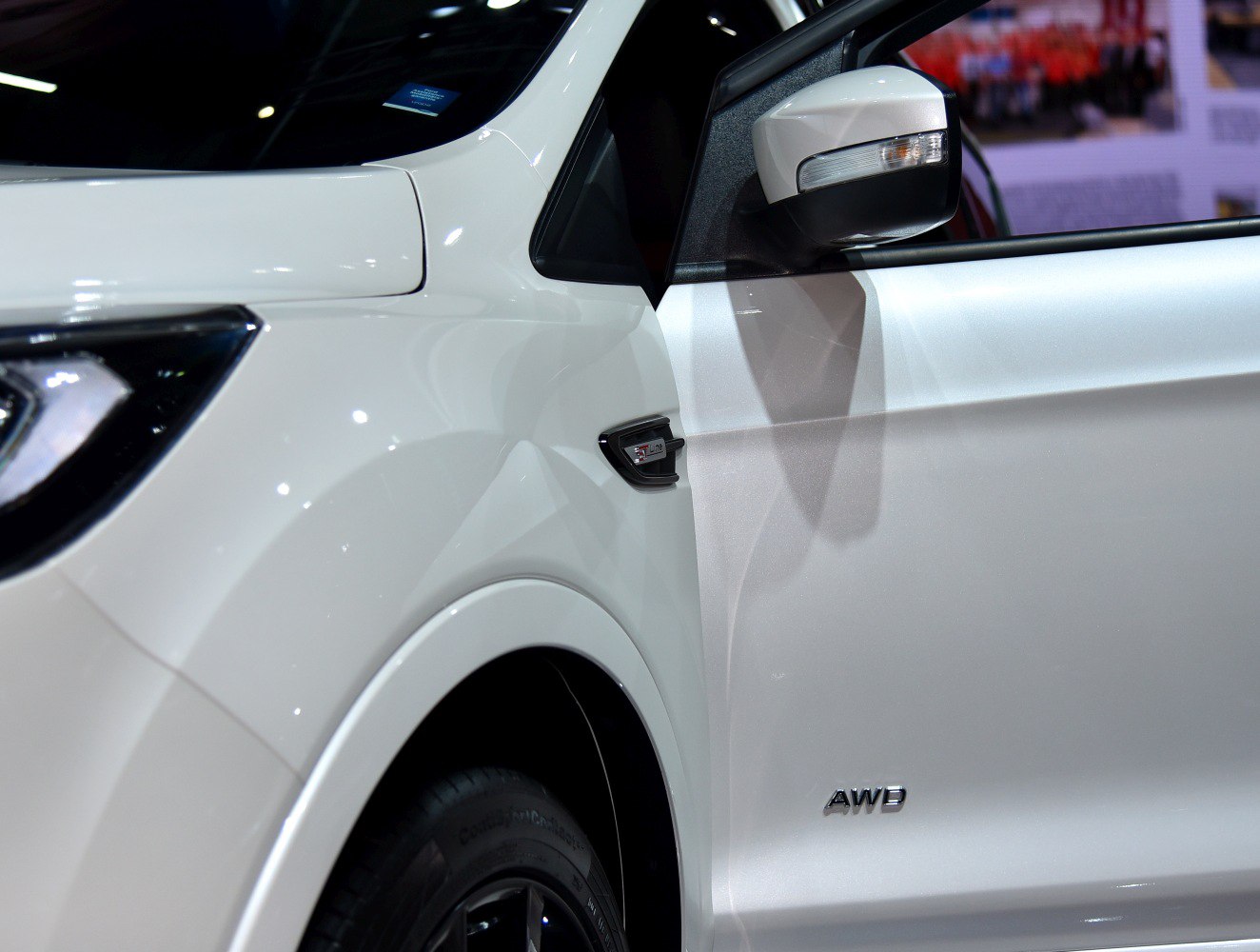 Close-up of AWD badge and side mirror with turn signal on white SUV.