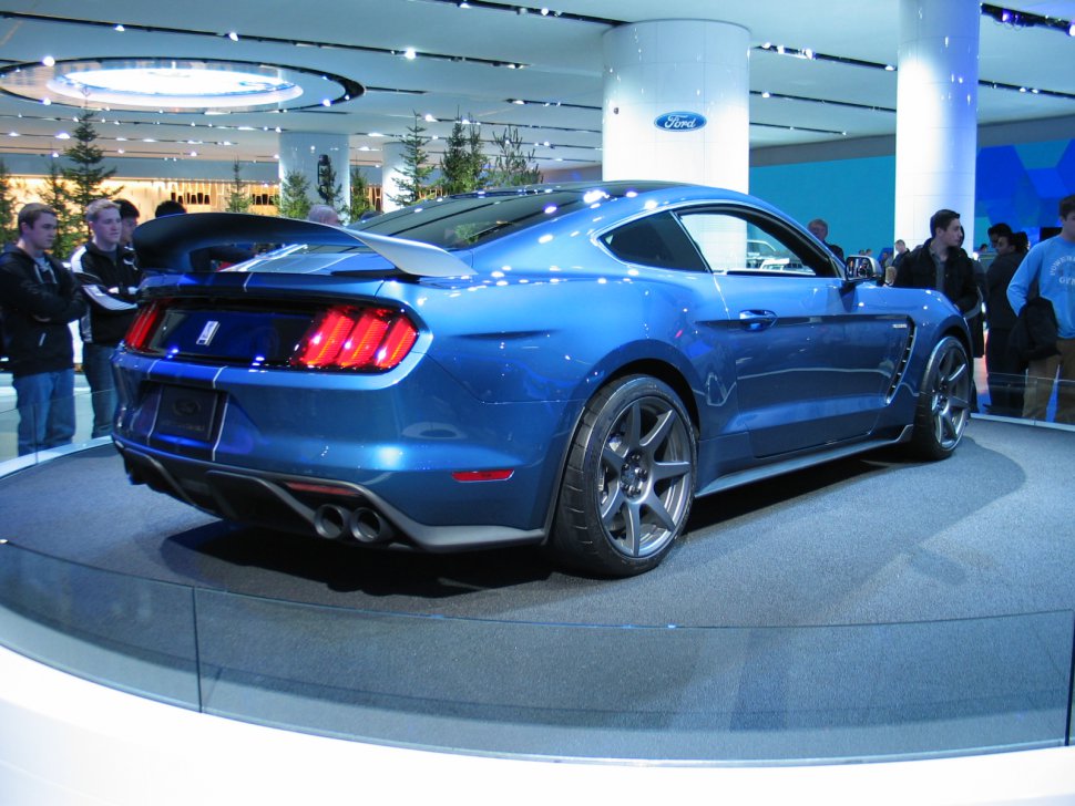 Rear and side view of blue sports coupe with large spoiler and twin exhausts