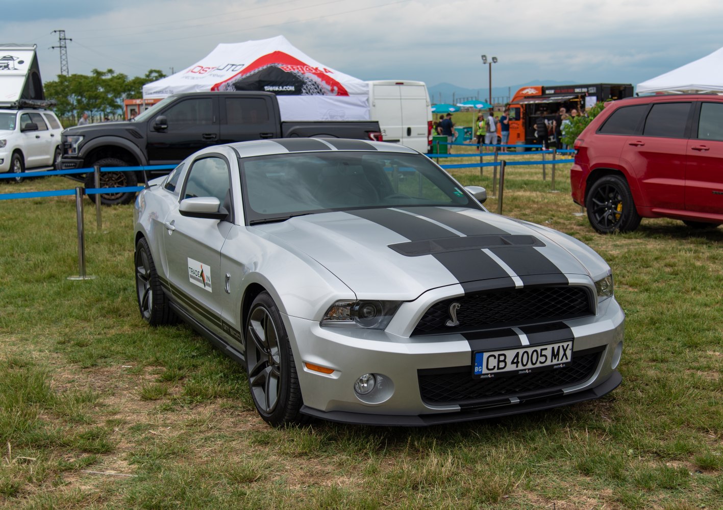 Silver coupe with black dual racing stripes and aggressive front grille