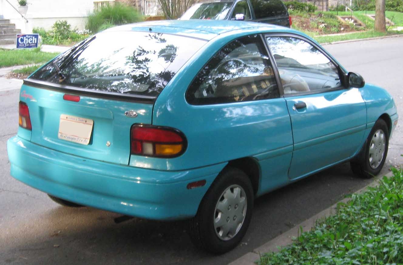 Rear-side view of a compact 1990s blue hatchback with rounded tail lights.