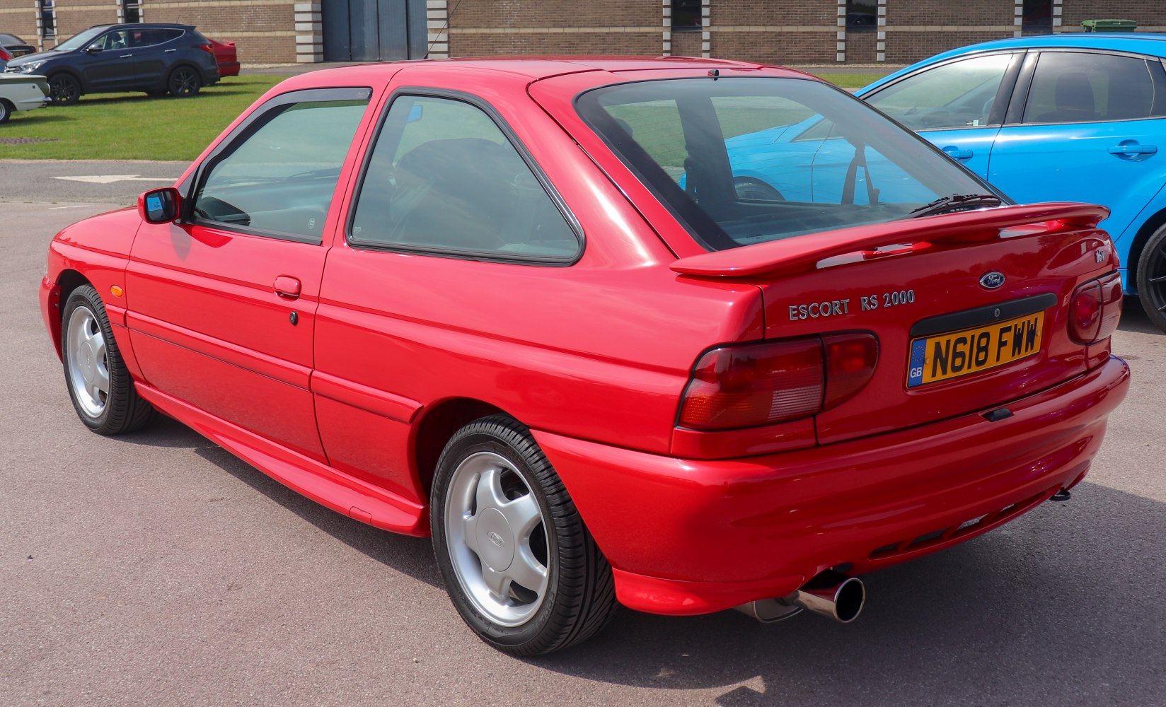 Red hatchback with sport spoiler and alloy wheels from rear side view
