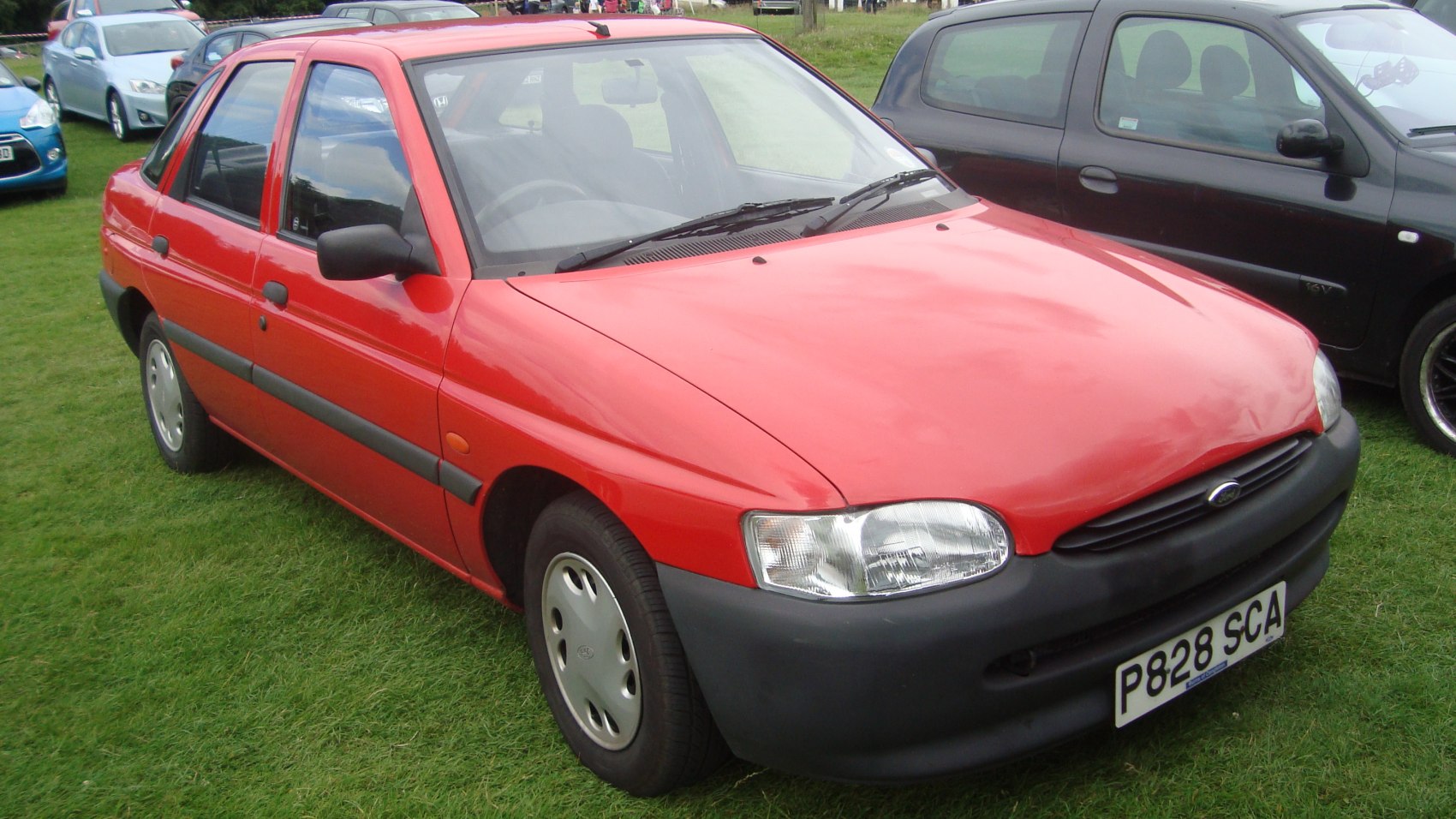 Red compact hatchback with black trim and rounded headlights