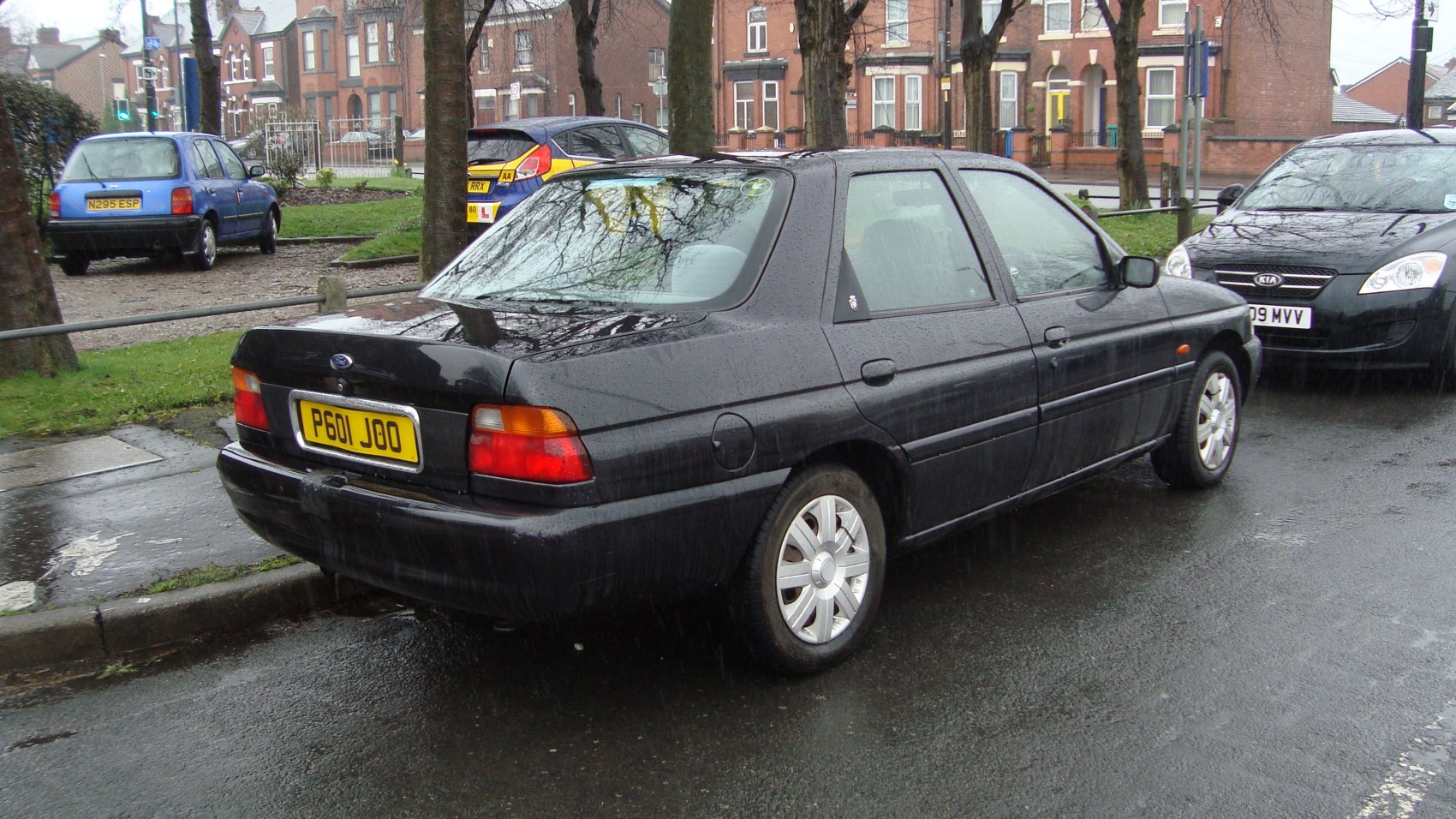Rear view of black sedan parked on a rainy street