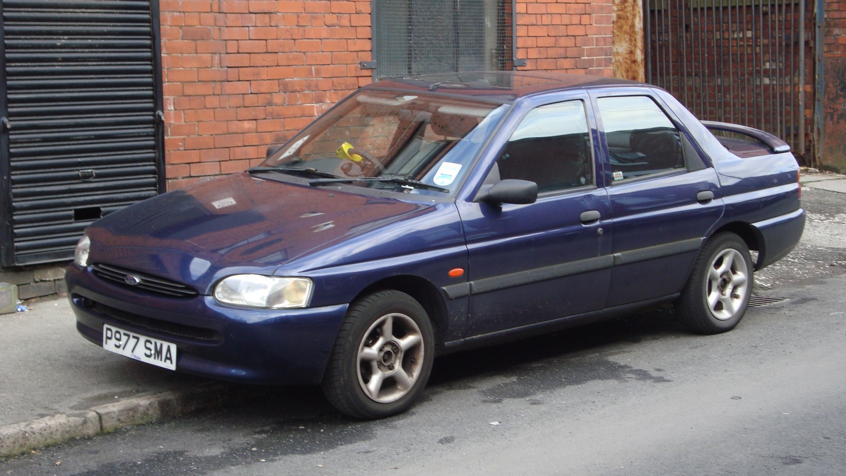 Blue four-door sedan parked by curb with alloy wheels