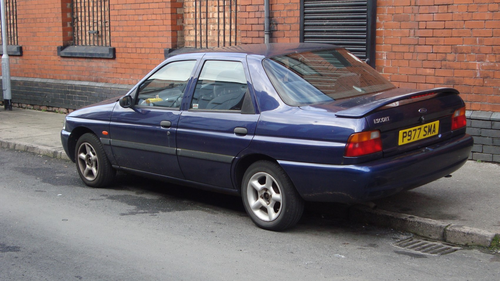 Rear side view of sedan with spoiler and alloy wheels