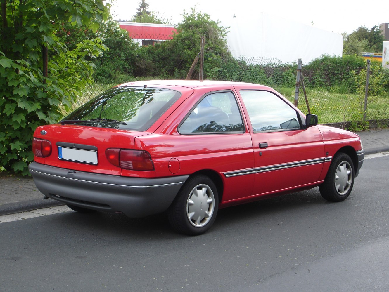 Rear side view of red hatchback with distinct tail lights and compact design.
