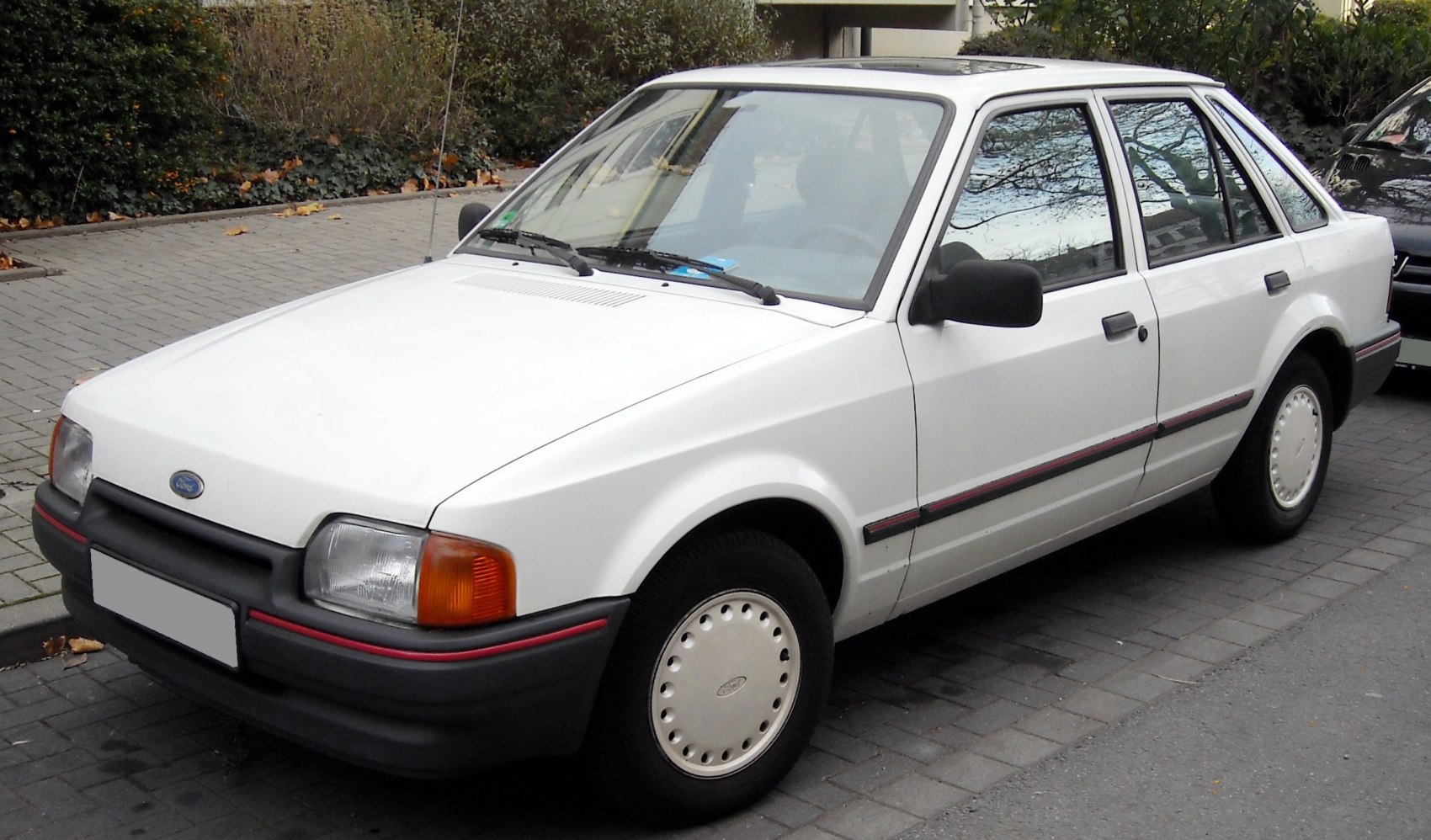 Compact sedan with angular design, integrated bumper, and traditional hubcaps