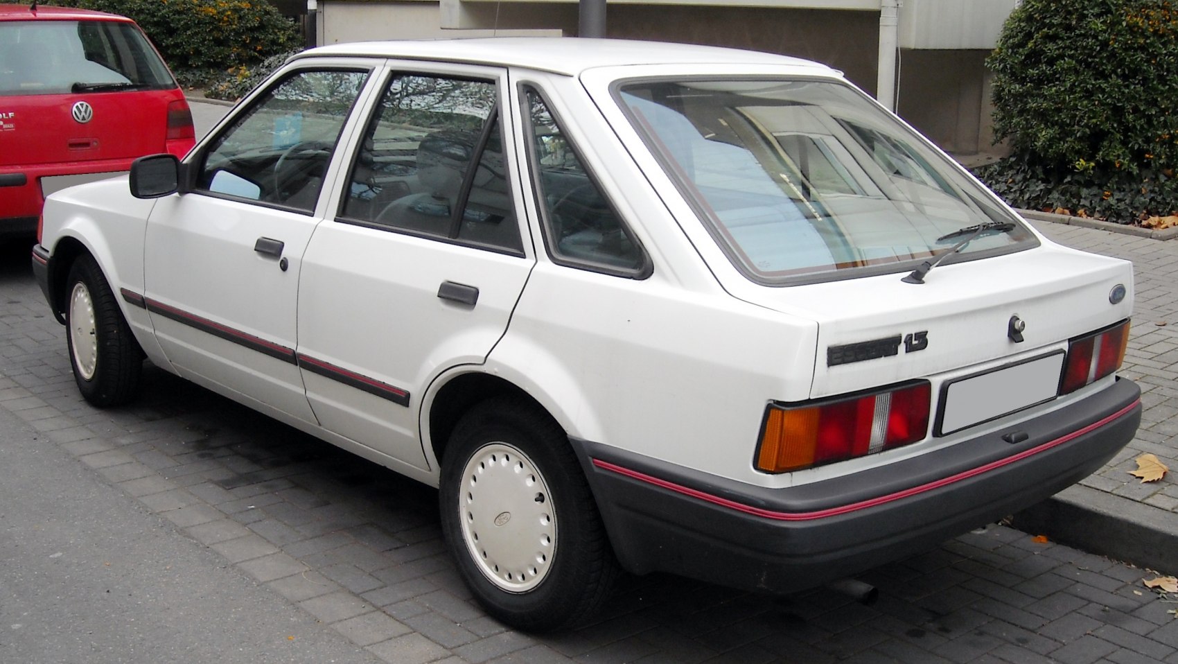 Rear and side view of a sharp-angled 1980s sedan with simple hubcaps.