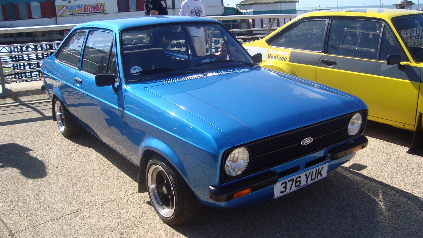 Blue vintage compact hatchback with round headlights and black grille.
